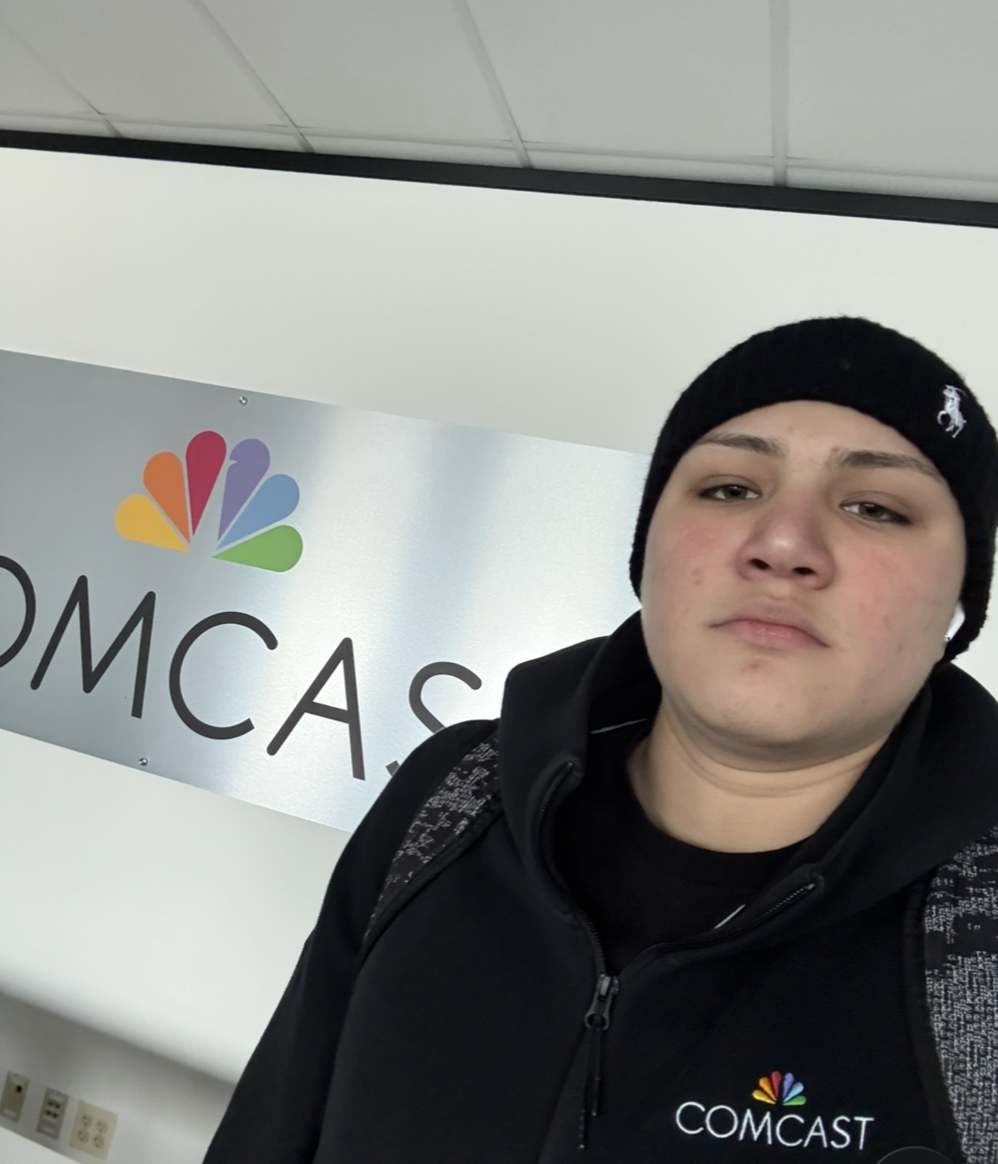 Charles in a Comcast jacket in front of the Comcast logo