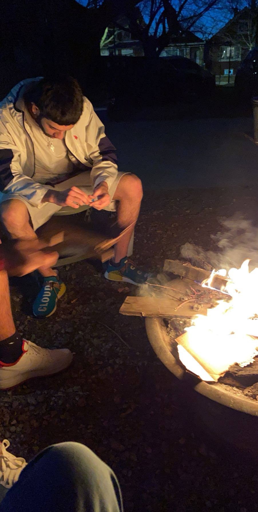 Friends gathered around a backyard campfire at night