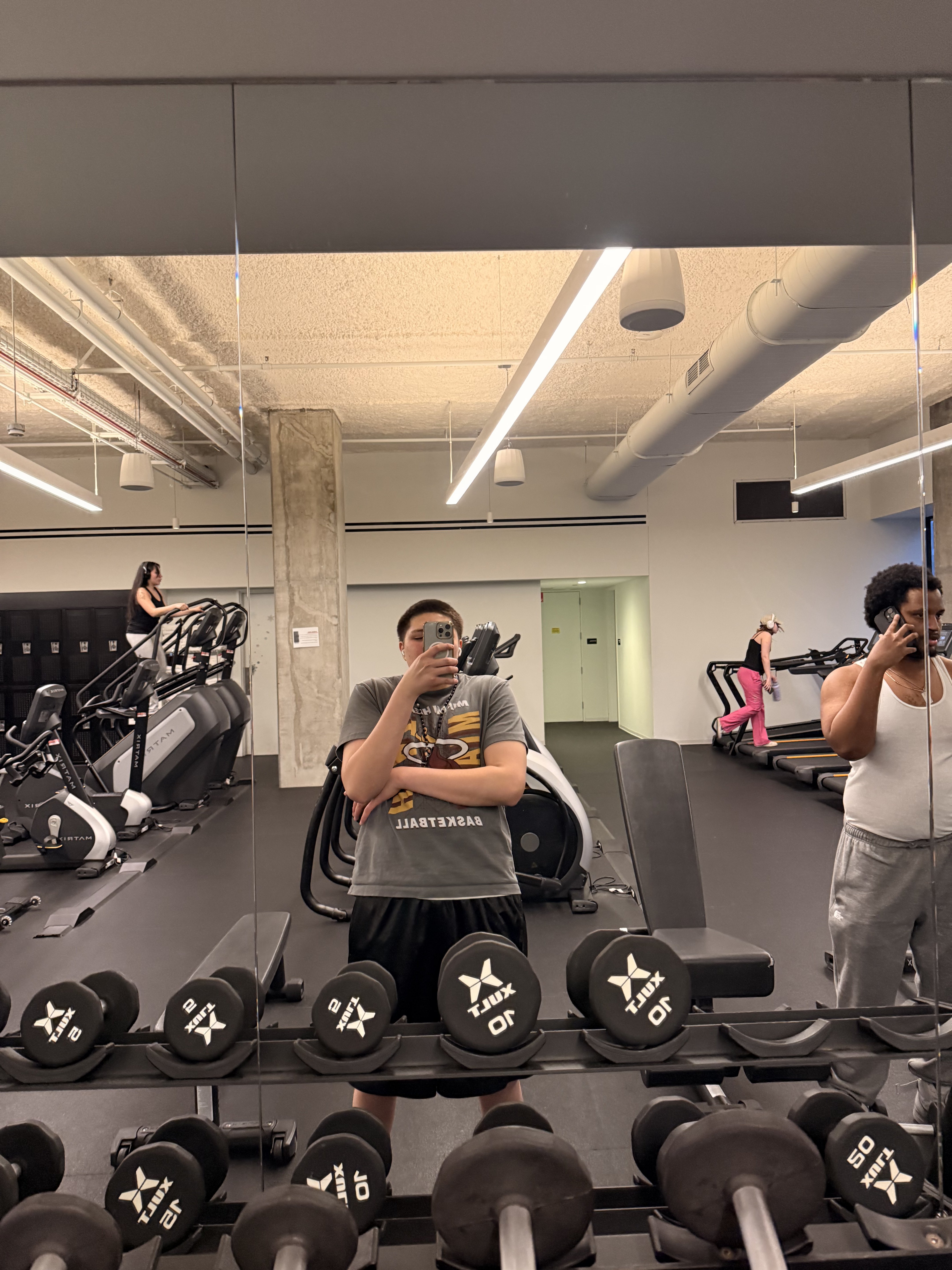 Mirror selfie in a gym with dumbbells in the foreground
